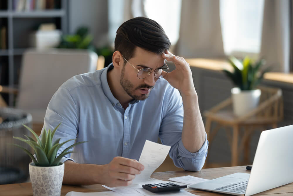 a man sitting in his office looking at expensive car bills on his computer