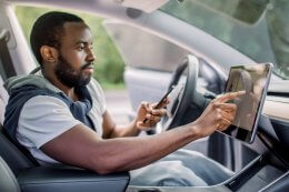 a man with a phone sits at the driver seat of his electric car and used the console