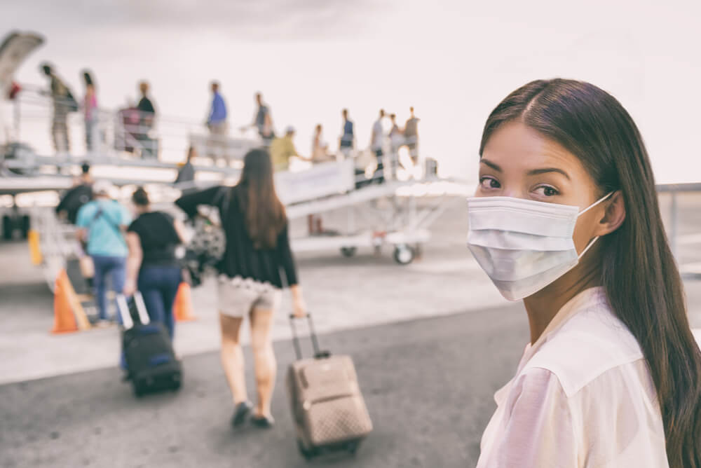 masked woman boarding a plane