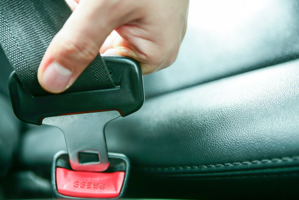 a close up of a hand putting a seatbelt buckle into a clasp