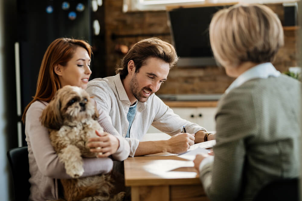 A couple holding their dog and checking their policy for pet insurance exclusions