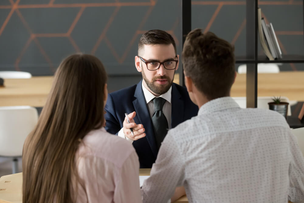 Two people planning a will with a solicitor and discussing life insurance beneficiary options
