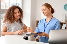 Nurse explaining to patient at reception holding a paper board and pen