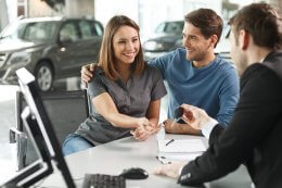 Woman is given car key by salesperson at car dealership