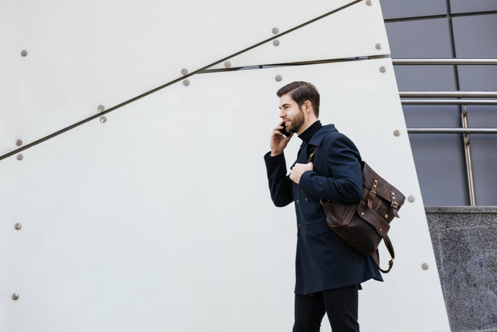 A man talking on mobile phone carrying a satchel