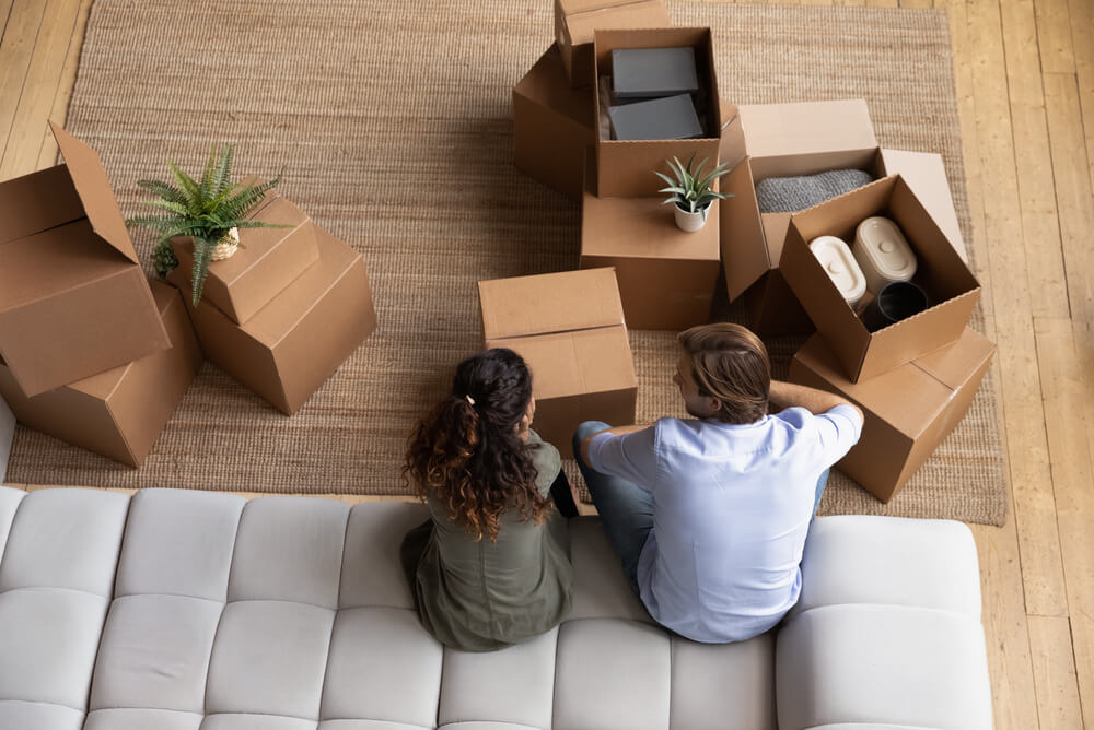 Renters sitting on a couch unpacking boxes