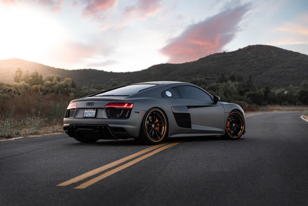 a grey Audi on a country road at sunset