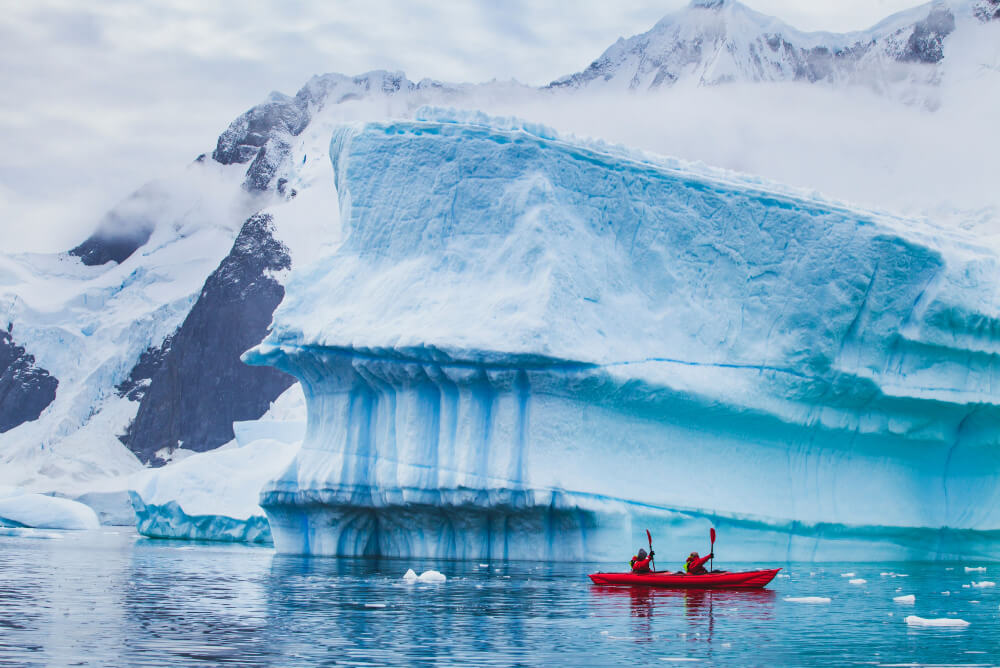 Kayaking by an iceberg in Antarctica