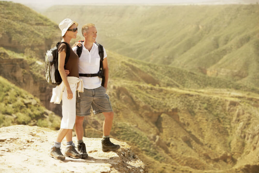 Middle aged couple hiking with travel insurance