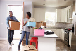 Couple carry moving boxes into their kitchen