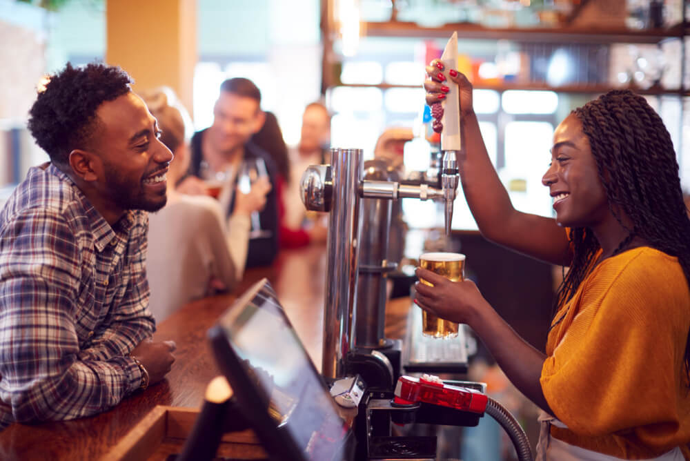 Woman pouring drink for a customer in a bar