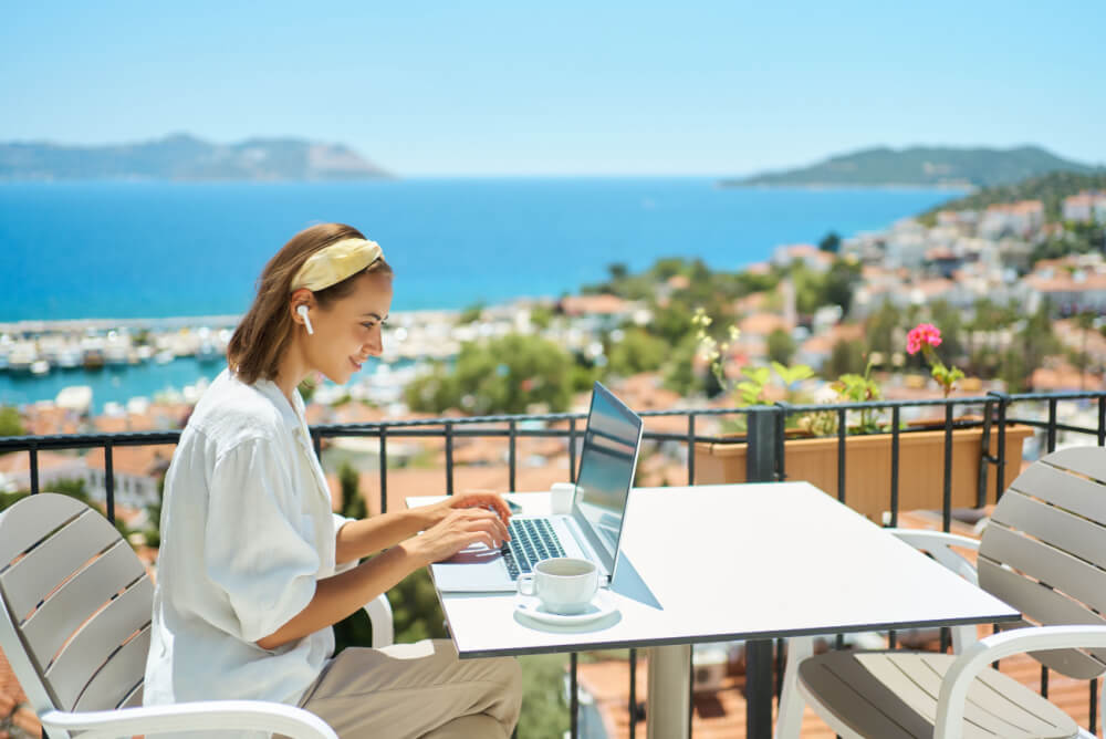 Woman working on a balcony overlooking the ocean