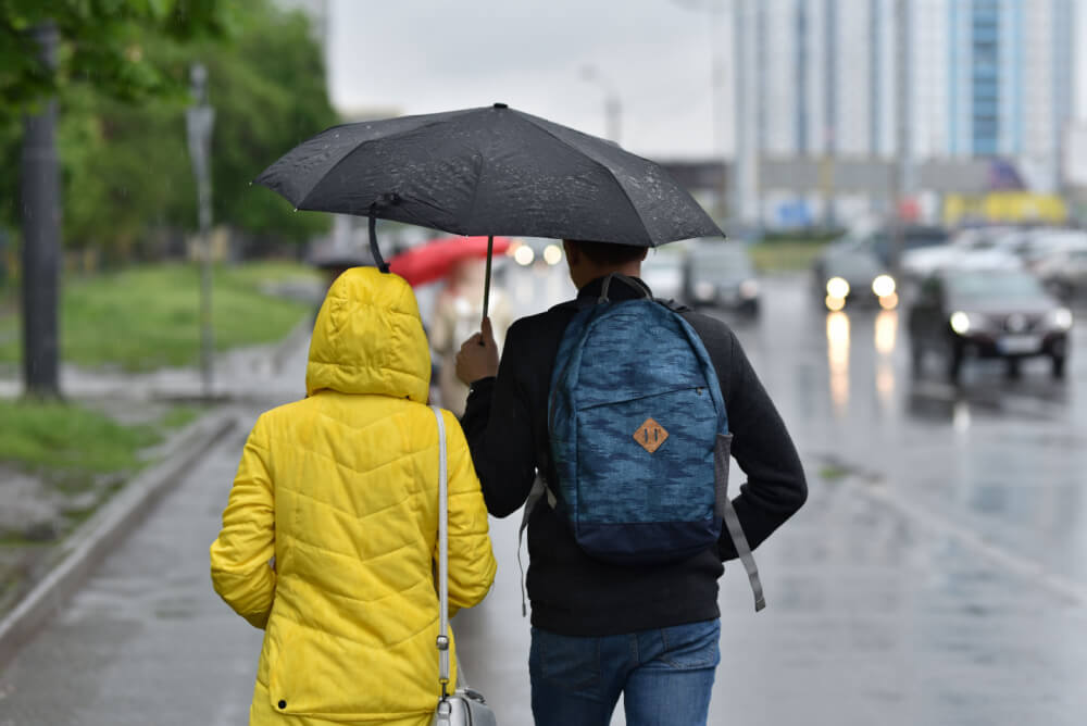 Couple with travel insurance with natural disaster cover in the rain