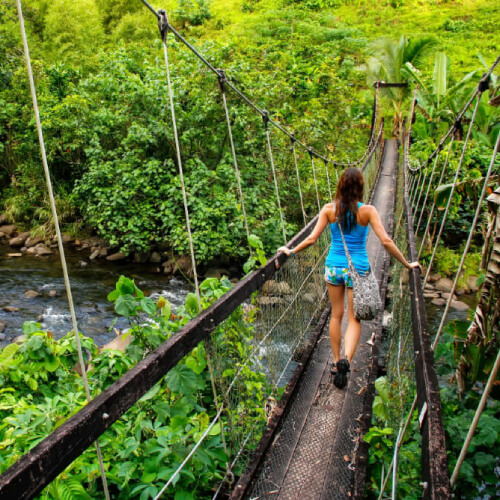 A woman walking over a suspension bridge Fiji.