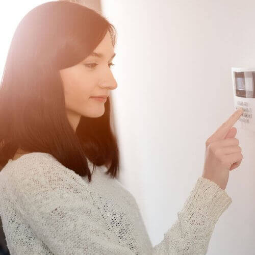 A young woman turning on alarm system which may be a factor that affects home and contents premium