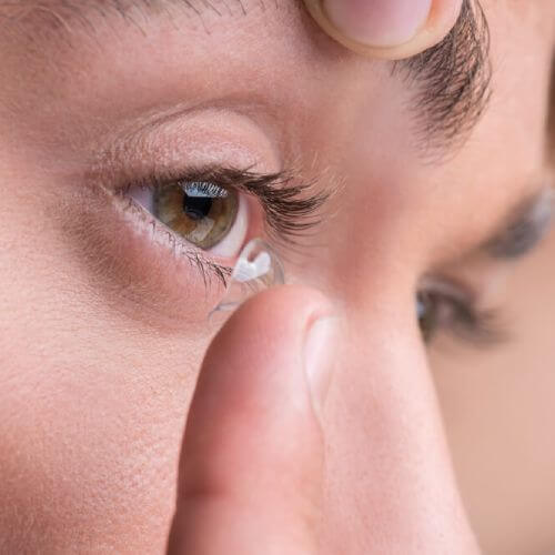 person puts in contact lenses