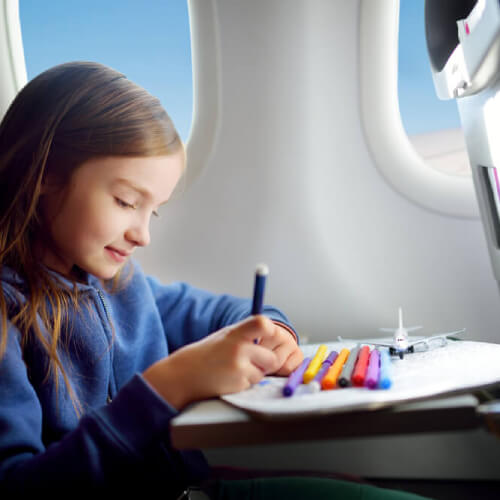Girl travelling alone colouring on plane