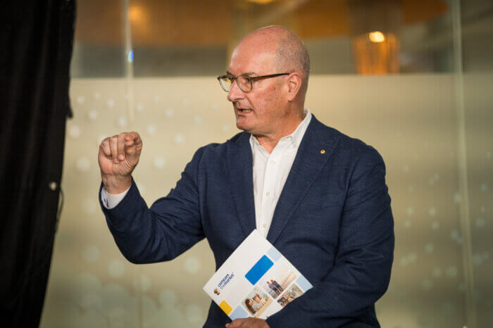 David Koch gestures while holding the Compare the Market 2025 Household Budget Barometer report